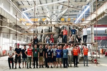 Large-scale bronze sculpture foundry workshop with professional manufacturing team and scaffolding for massive municipal and commercial projects