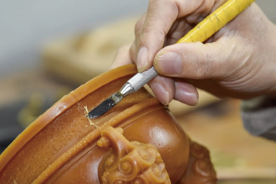 Artisan hand-chasing wax pattern details before casting