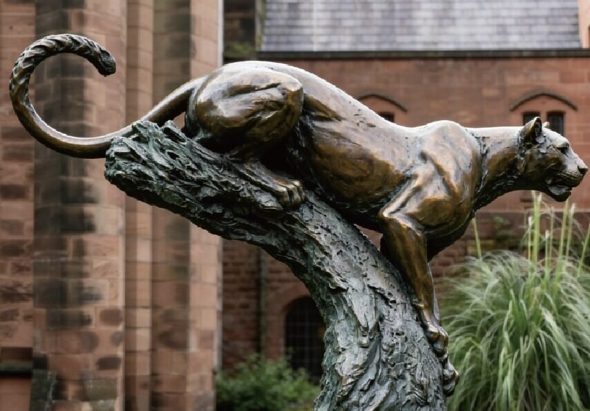custom bronze leopard statue on a tree trunk in an outdoor garden