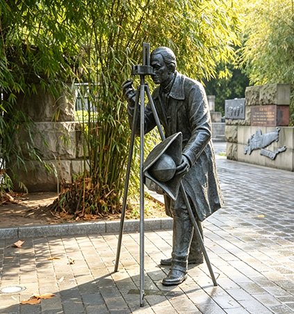 Realistic bronze figure statue in an outdoor park setting, demonstrating Minimal Maintenance Costs and a protective living finish through natural patina development.