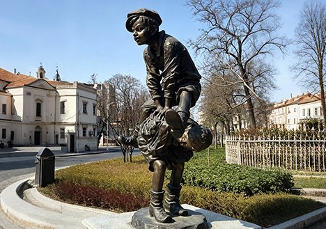 Realisti Custom Bronze Sculptures of a playing child in an urban plaza, showcasing our 88% tin bronze quality and antique patination for landscape architecture projects.