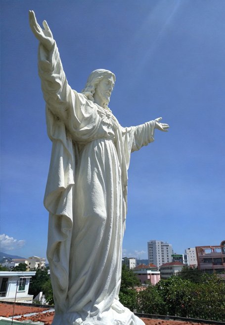 Large-scale white Jesus Christ statue overlooking an urban landscape, representing the unwavering trust of 80% of China's temples and religious institutions in Wensculp's bespoke sacred art for Christian Churches , Buddhist Temples , and Islamic Mosques .