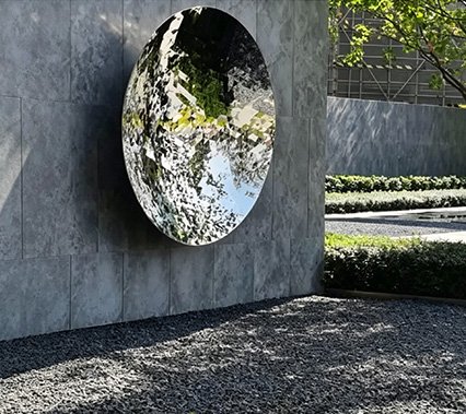 Contemporary mirror-polished stainless steel wall installation in an outdoor hotel courtyard, illustrating why Wensculp has Received a 95% approval rating from Hotels & Hospitality experts and Interior Design Firms / FF&E Designers .