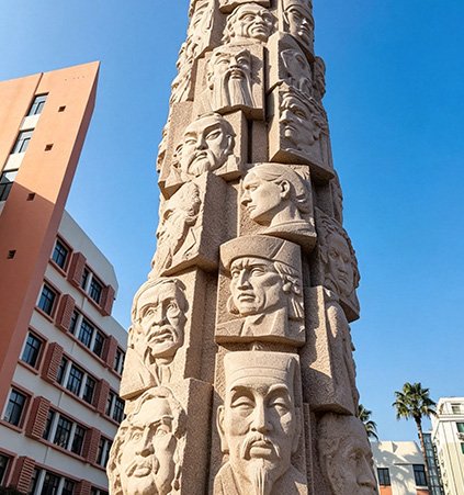 Tall bronze relief monument featuring historical scholars, illustrating our Durable Process using 88% tin bronze to withstand UV and acid rain on university campuses.