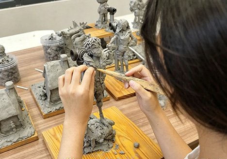 A master artisan meticulously refining an intricate clay sculpture for Fine Art Replication & Restoration, showcasing Wensculp's high-fidelity reproduction using 3D scanning and lost-wax casting.