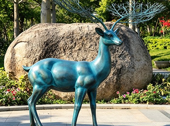 A realistic teal bronze stag sculpture in a garden, illustrating Wensculp's expertise in Choosing Coloring Techniques for Custom Sculptures and providing Outdoor Environmental Resilience Solutions.