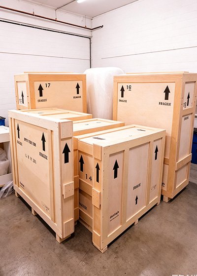 Heavy-duty export wooden crates illustrating Steel-Reinforced Composite Crating and International Wood Packaging Compliance (ISPM 15) for monumental sculptures, featuring a Vibration-Damping & Secure Locking System.