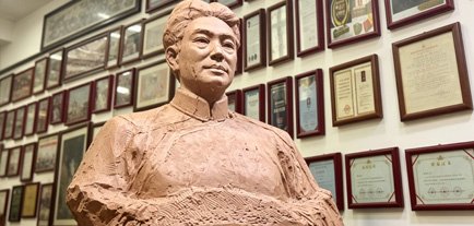 A finished clay bust of a historical figure in front of a wall of award certificates, providing answers to the regarding design flexibility.