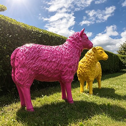 pink and yellow fiberglass sheep statues on grass