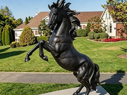 black rearing fiberglass horse statue on a lawn