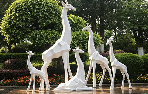 white low-poly fiberglass giraffe statues in a garden