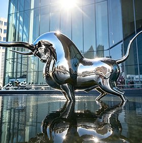 Mirror-polished stainless steel bull sculpture at a corporate plaza