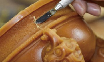Close-up of detailed hand-carving on a bronze sculpture surface